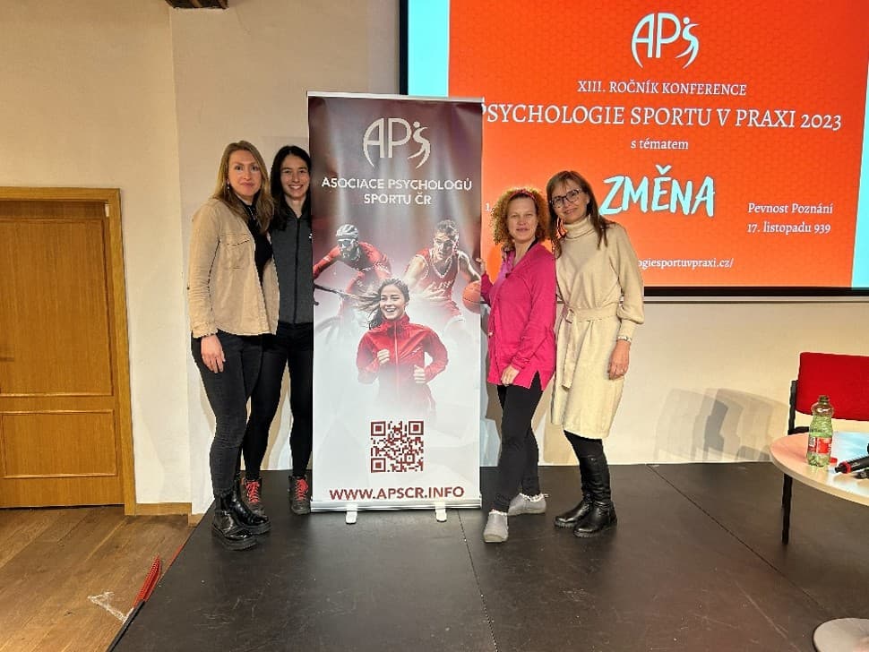 Jana Harvanová s kolegyněmi u banneru Asociace psychologů sportu ČR na konferenci Psychologie sportu v praxi 2023